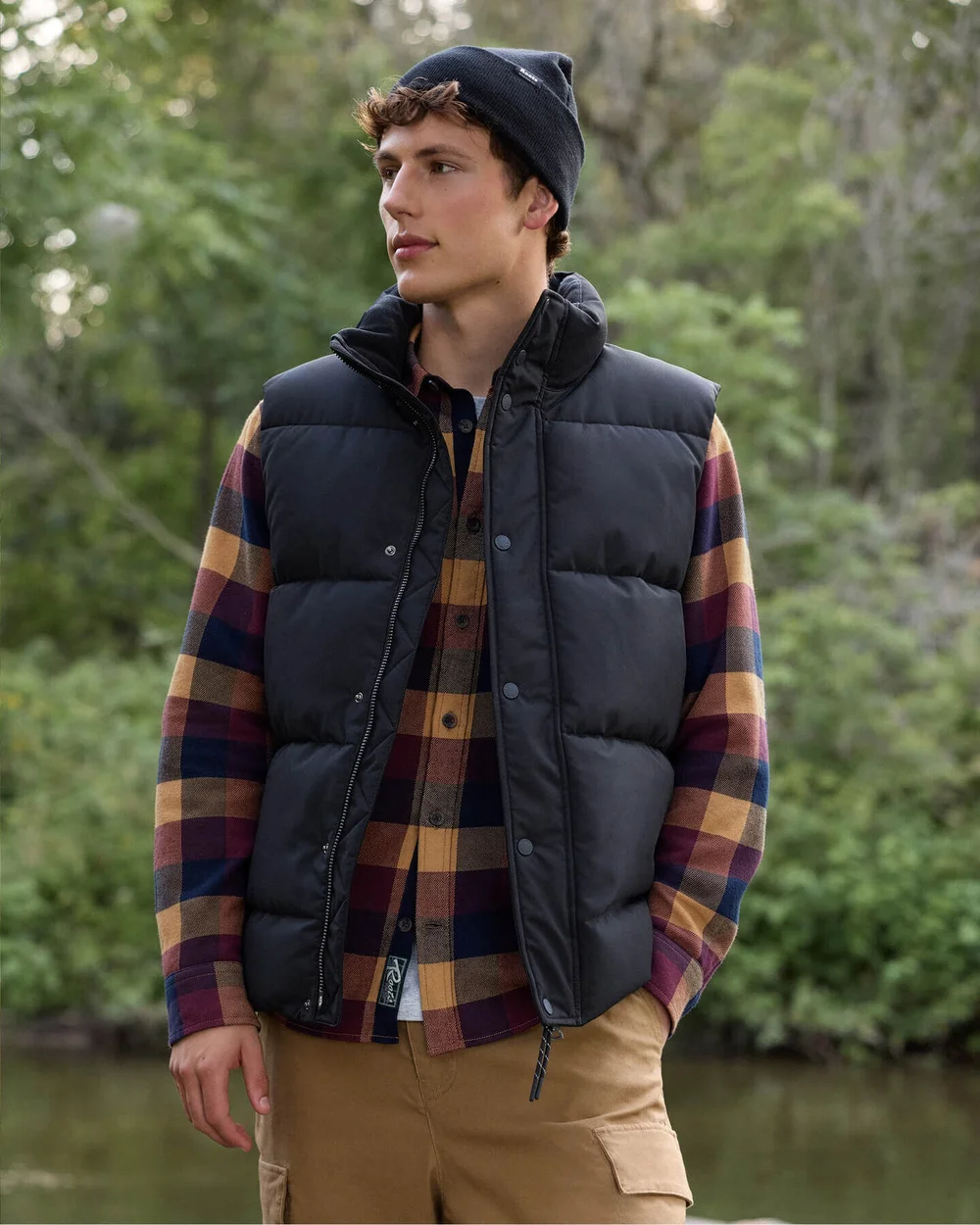 Man in a quilted vest and plaid shirt in the forest